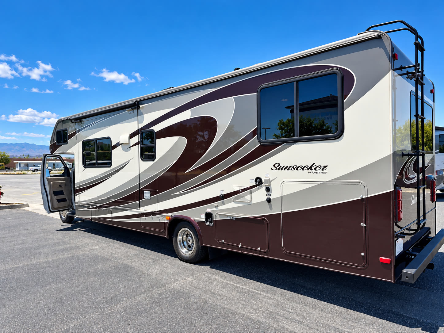 Side exterior view of the white-and-burgundy Sunseeker RV with entry door open and rear bike rack.